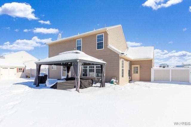 snow covered rear of property with a storage shed and a gazebo