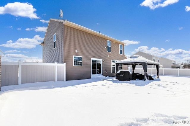 snow covered back of property with a gazebo