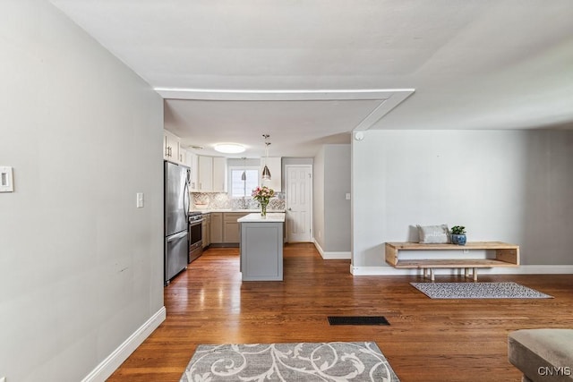 kitchen with appliances with stainless steel finishes, gray cabinets, dark hardwood / wood-style flooring, hanging light fixtures, and tasteful backsplash