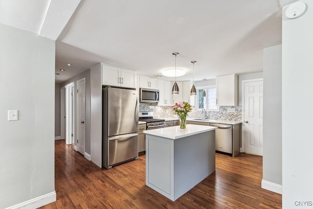 kitchen featuring appliances with stainless steel finishes, pendant lighting, a center island, sink, and white cabinetry