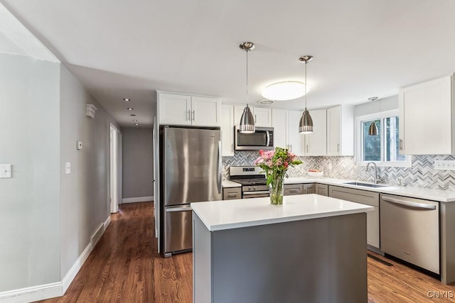 kitchen with white cabinetry, a center island, sink, appliances with stainless steel finishes, and pendant lighting