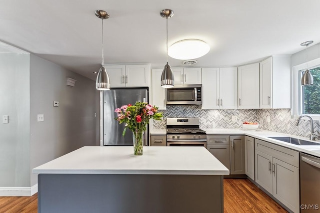 kitchen with decorative light fixtures, sink, stainless steel appliances, and a center island