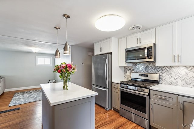 kitchen featuring gray cabinets, light wood-type flooring, pendant lighting, and stainless steel appliances