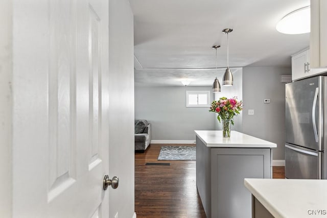 kitchen featuring a center island, stainless steel refrigerator, dark wood-type flooring, white cabinets, and pendant lighting