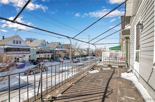 snow covered patio with a residential view and fence