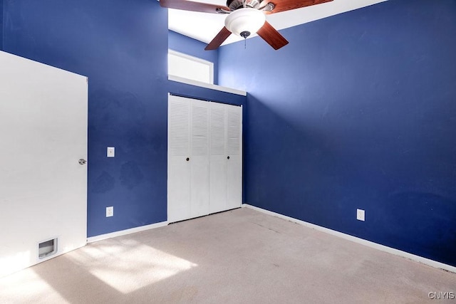 unfurnished bedroom featuring a closet, ceiling fan, a high ceiling, and light colored carpet