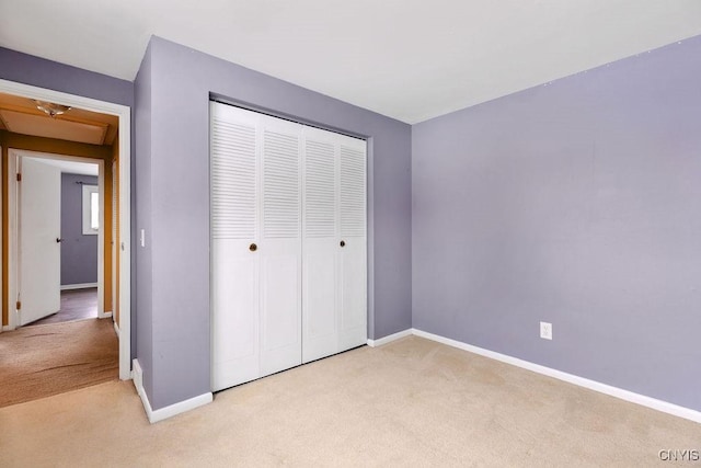 unfurnished bedroom with light carpet and a closet