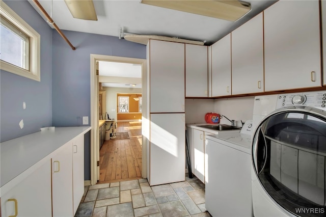 washroom with cabinets, washer and dryer, and sink