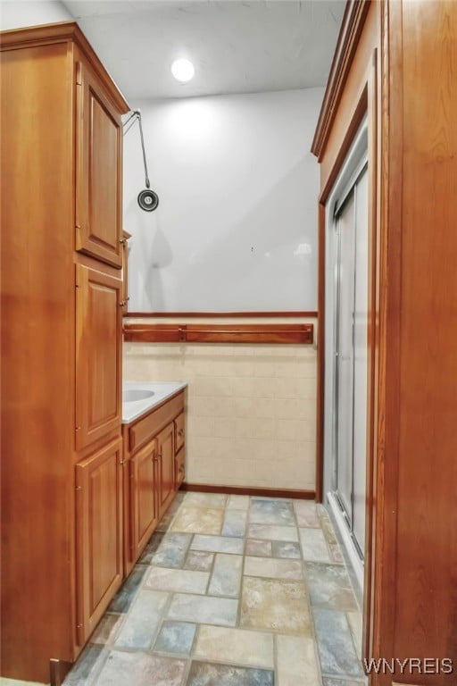 bathroom with tile walls, walk in shower, and vanity