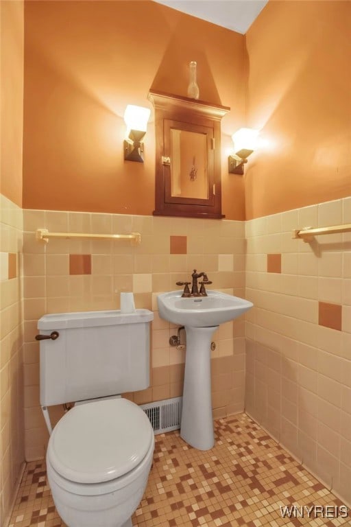 bathroom featuring toilet and tile walls