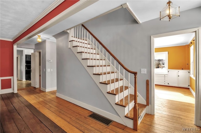 stairs with ornamental molding and wood-type flooring