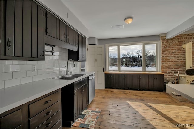 kitchen with sink, dark brown cabinetry, backsplash, and light wood-type flooring