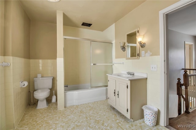 full bathroom featuring tile walls, vanity, combined bath / shower with glass door, toilet, and tile patterned floors