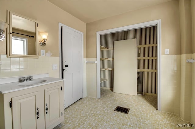 bathroom with tile walls, tile patterned flooring, and vanity