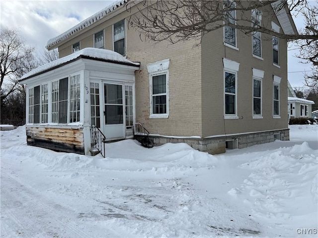 view of snow covered exterior with a sunroom