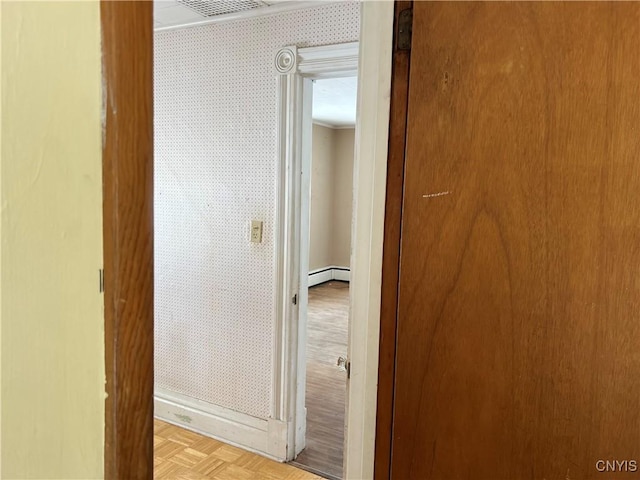 corridor featuring a baseboard heating unit and light parquet floors