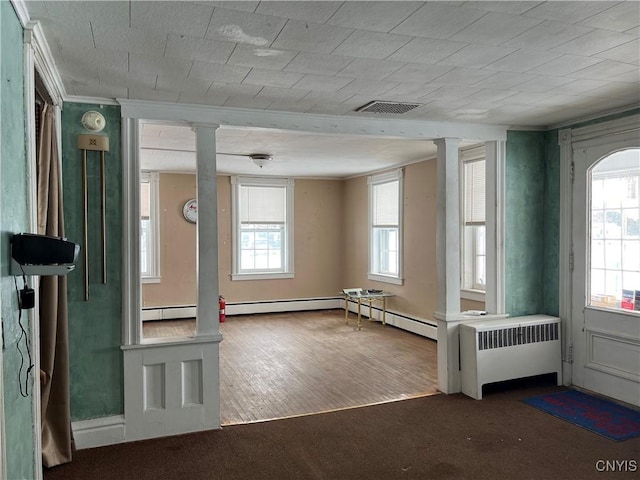 empty room with hardwood / wood-style floors, ornate columns, and radiator