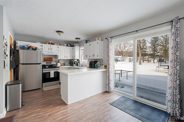 kitchen featuring white cabinetry, kitchen peninsula, stainless steel appliances, and wood-type flooring