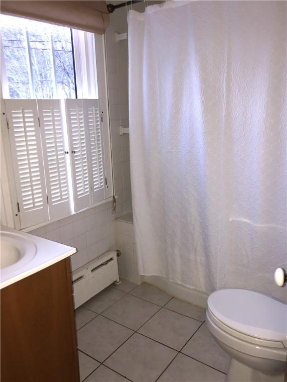 bathroom featuring a baseboard radiator, tile walls, shower / bath combination with curtain, toilet, and tile patterned flooring
