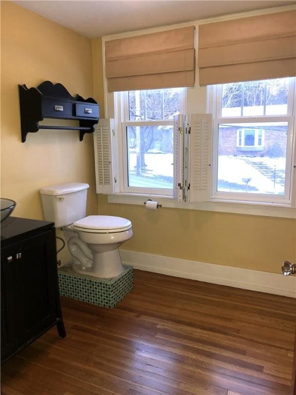 half bath with wood-type flooring, baseboards, and toilet