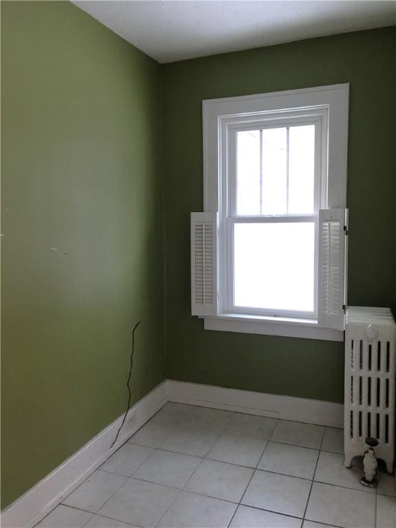 unfurnished room with radiator, baseboards, and light tile patterned floors