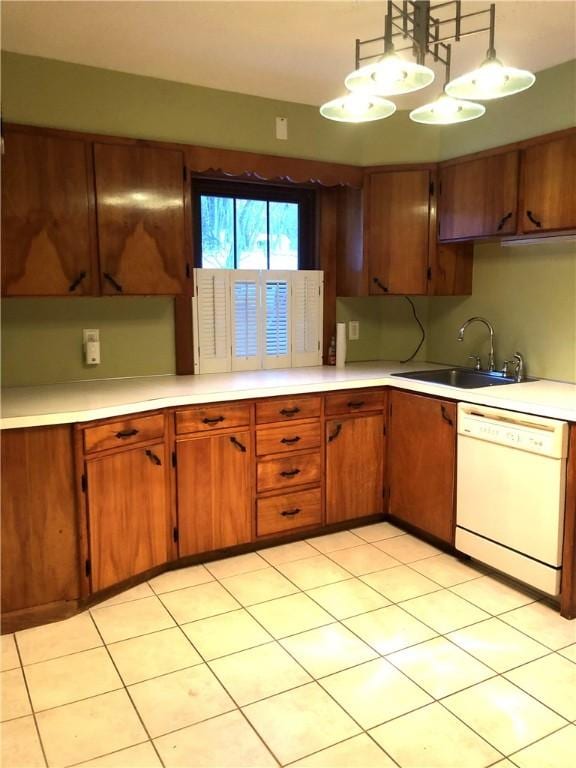 kitchen featuring light countertops, a sink, brown cabinetry, dishwasher, and hanging light fixtures