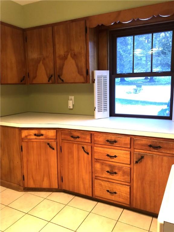 kitchen with brown cabinetry, light countertops, and light tile patterned flooring