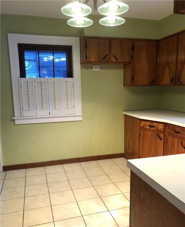 kitchen featuring light countertops, baseboards, brown cabinets, and light tile patterned floors