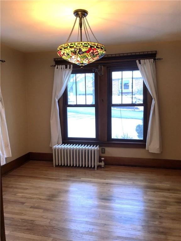 unfurnished dining area with radiator, wood finished floors, and baseboards