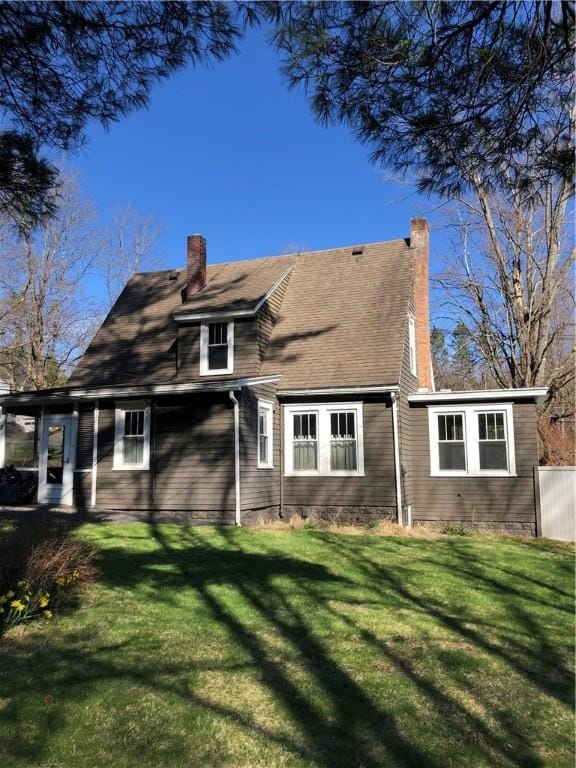 rear view of property featuring a chimney and a yard
