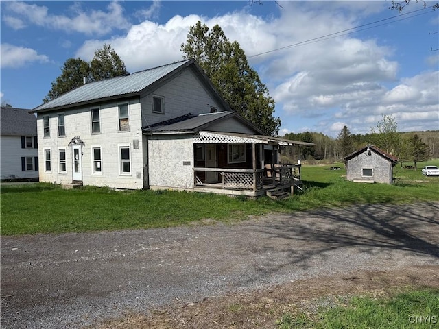 view of front of house with a porch, a front lawn, and metal roof