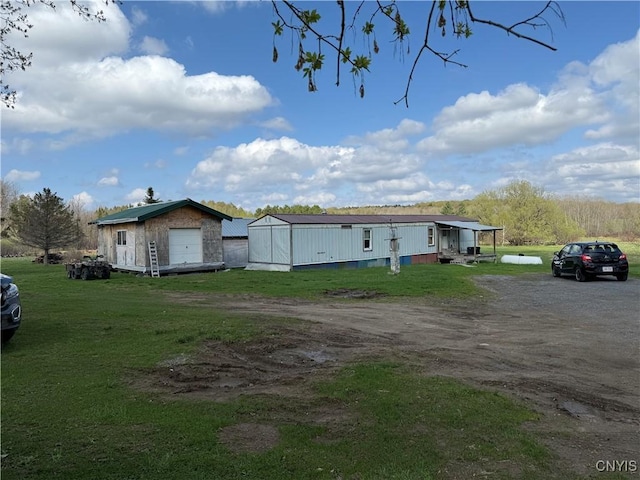view of front facade featuring dirt driveway, a front lawn, an outbuilding, and a detached garage