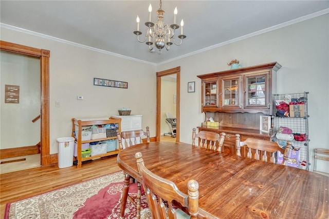 dining room with light wood-type flooring, a chandelier, and crown molding