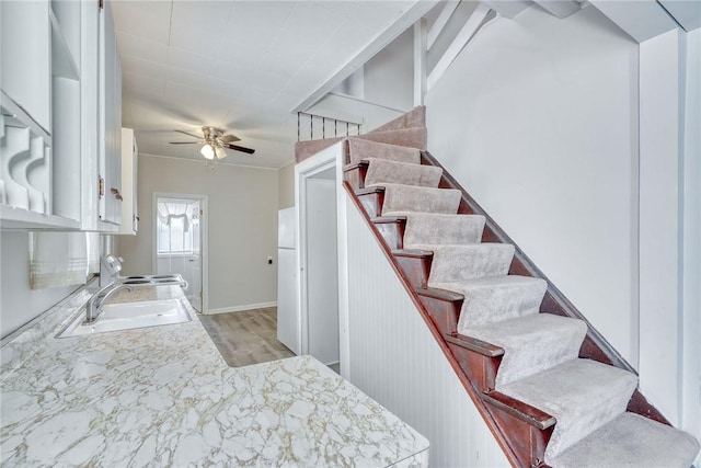 stairway with sink, hardwood / wood-style flooring, and ceiling fan