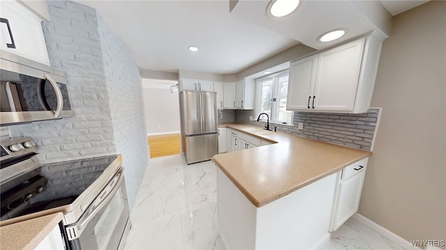 kitchen with appliances with stainless steel finishes, decorative backsplash, sink, and white cabinetry