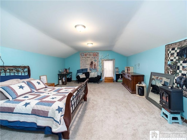 bedroom featuring light carpet, a wood stove, and vaulted ceiling