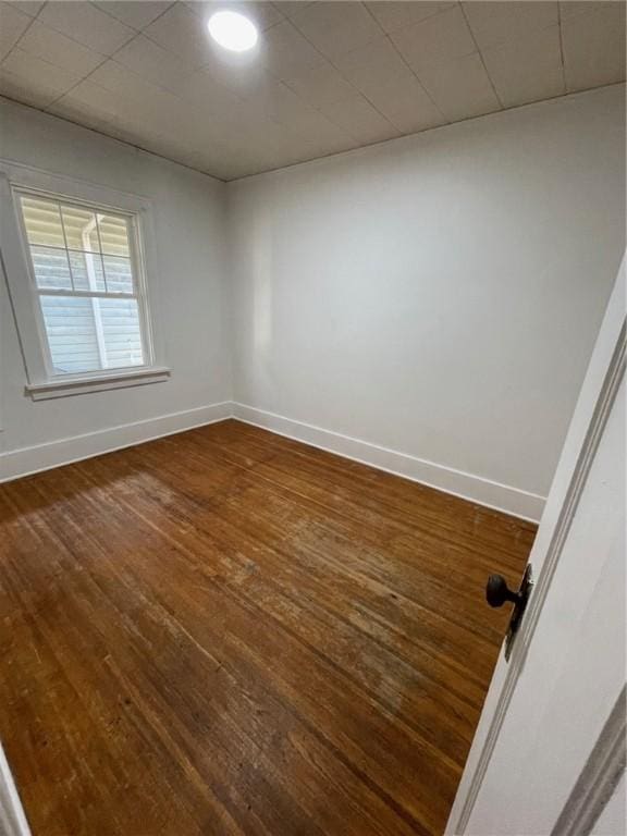 unfurnished room with baseboards and dark wood-type flooring