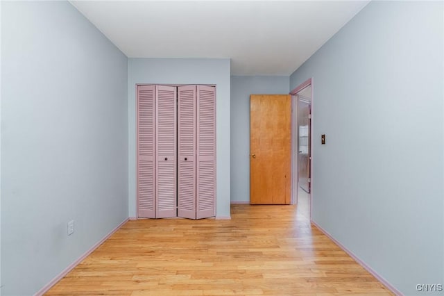 unfurnished bedroom with light wood-type flooring and a closet