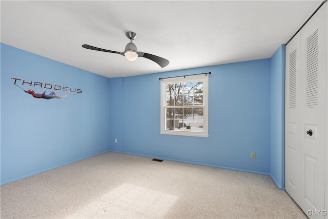 unfurnished bedroom with a closet, light colored carpet, and ceiling fan