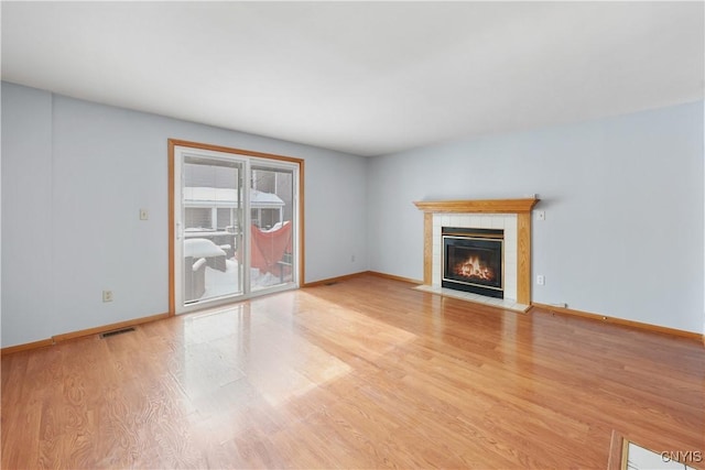 unfurnished living room featuring light hardwood / wood-style floors and a tile fireplace