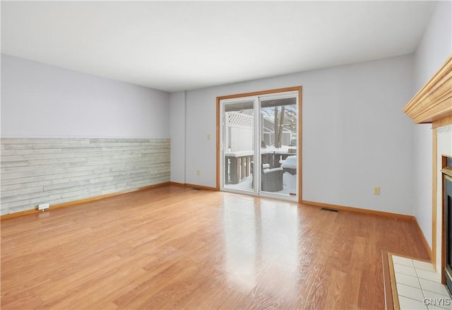 spare room featuring a fireplace and light wood-type flooring