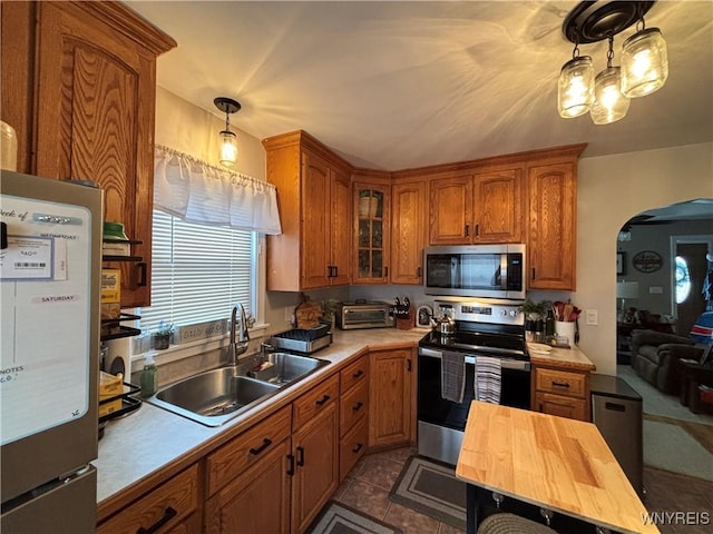 kitchen featuring appliances with stainless steel finishes, tile patterned flooring, hanging light fixtures, wood counters, and sink