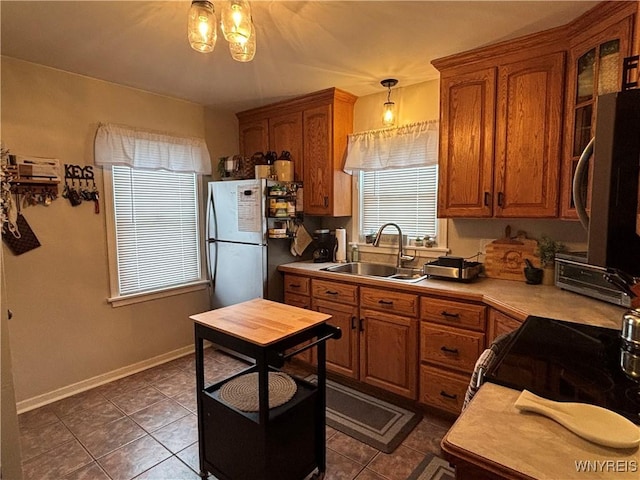 kitchen with hanging light fixtures, appliances with stainless steel finishes, sink, and dark tile patterned floors