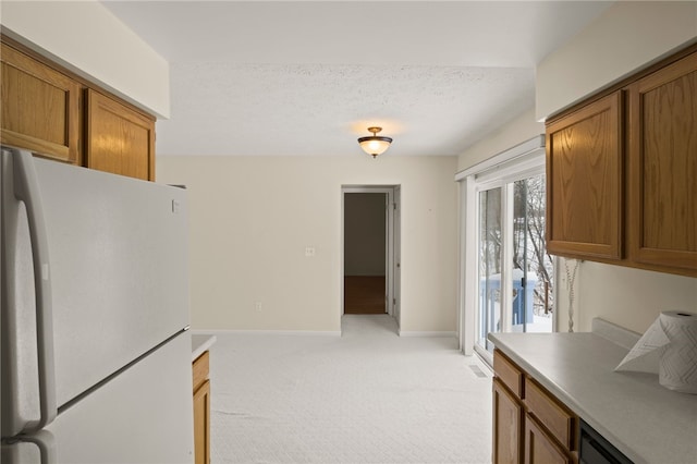 kitchen with white refrigerator, a textured ceiling, and light colored carpet