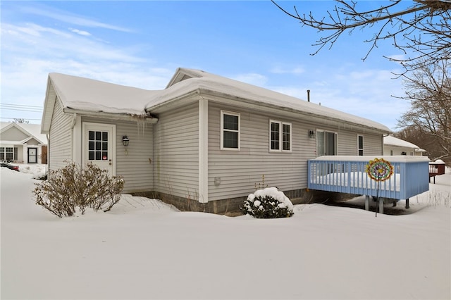 snow covered back of property with a wooden deck