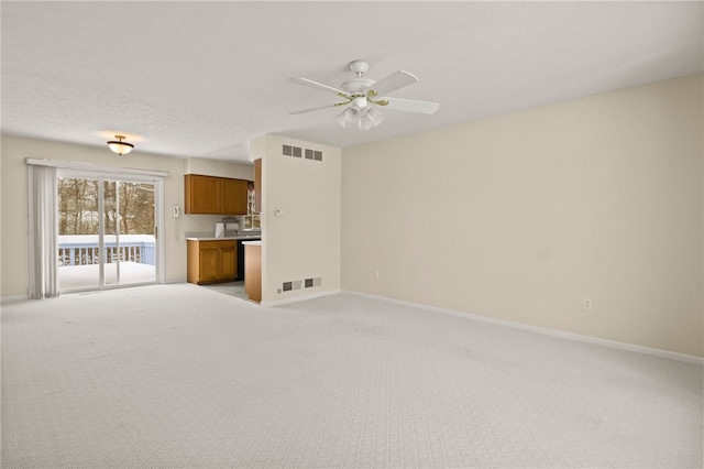 unfurnished living room featuring a textured ceiling, ceiling fan, and light colored carpet