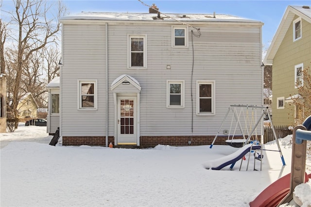 snow covered rear of property featuring a playground