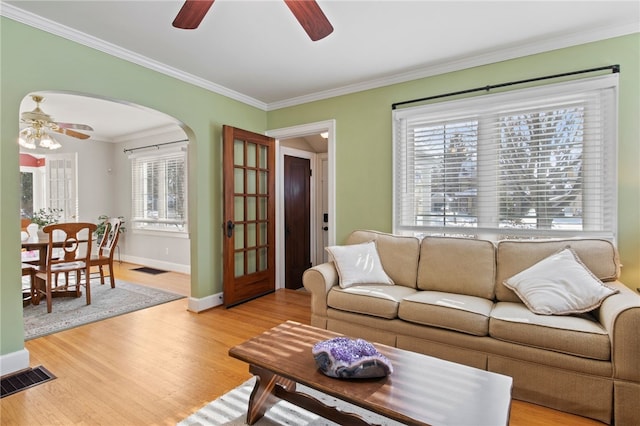 living room with light hardwood / wood-style flooring, ceiling fan, plenty of natural light, and ornamental molding