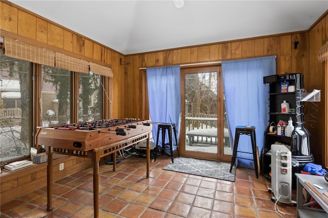 recreation room with wood walls, lofted ceiling, and light tile patterned flooring