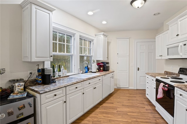 kitchen with sink, white cabinets, light hardwood / wood-style floors, light stone counters, and range with electric stovetop